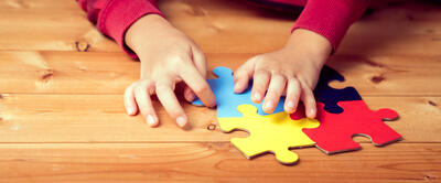 Kind met autisme maakt een puzzel, enkel de puzzel en de handen zijn zichtbaar