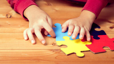 Kind met autisme maakt een puzzel, enkel de puzzel en de handen zijn zichtbaar
