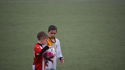 Twee jonge voetballers, de ene houdt een bal vast