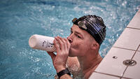 G-zwemmer Sam De Visser drinkt in het zwembad van zijn drinkbus tijdens een training