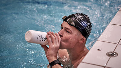 G-zwemmer Sam De Visser drinkt in het zwembad van zijn drinkbus tijdens een training